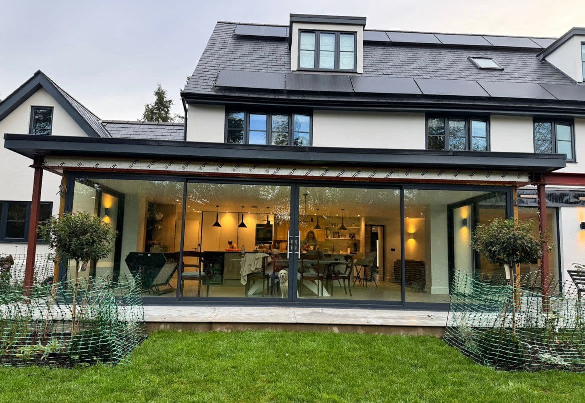Rear extension with black aluminium sliding doors at dusk