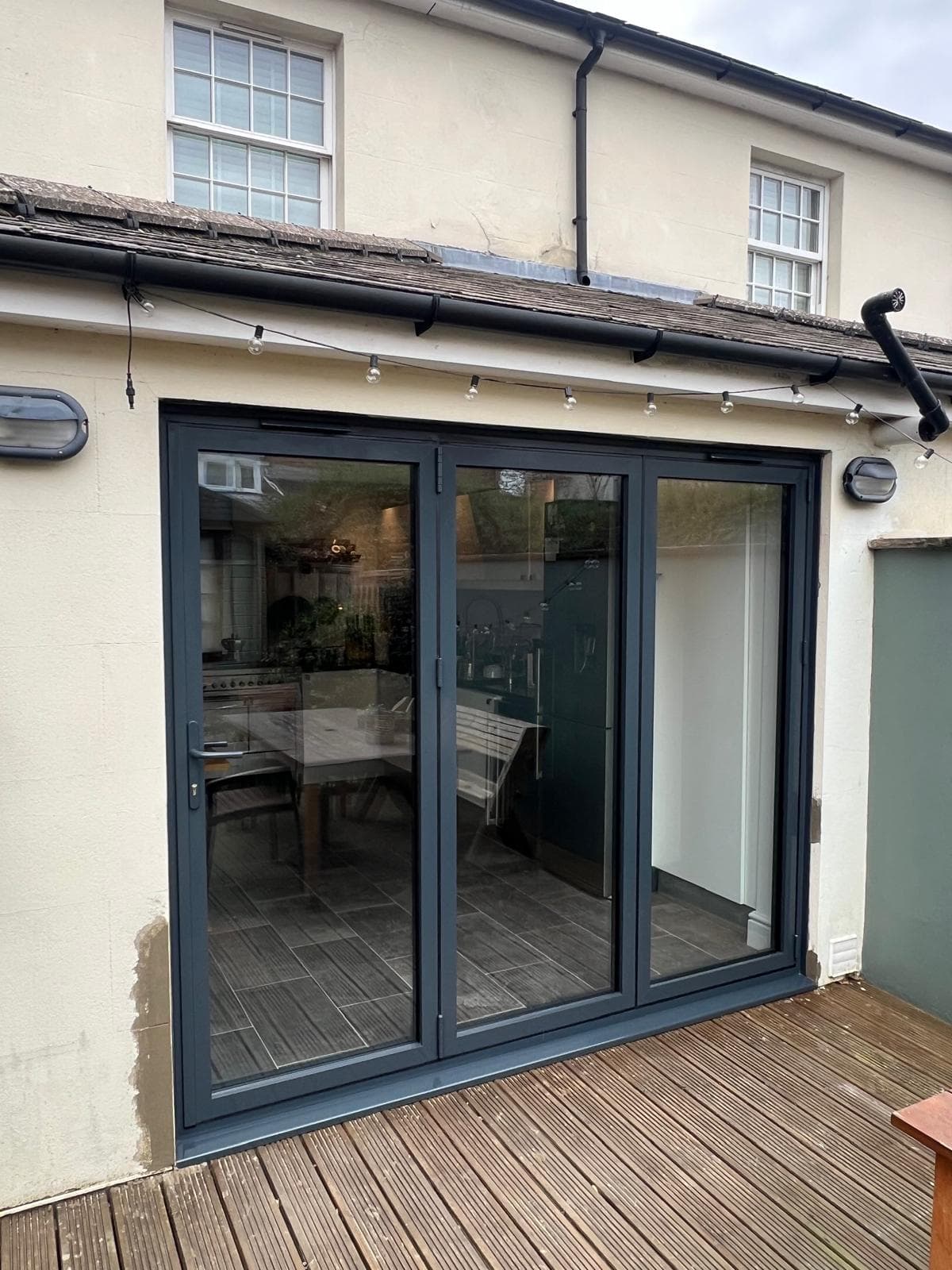 Smart Visofold aluminium bifold doors in anthracite grey, open to a Surrey garden